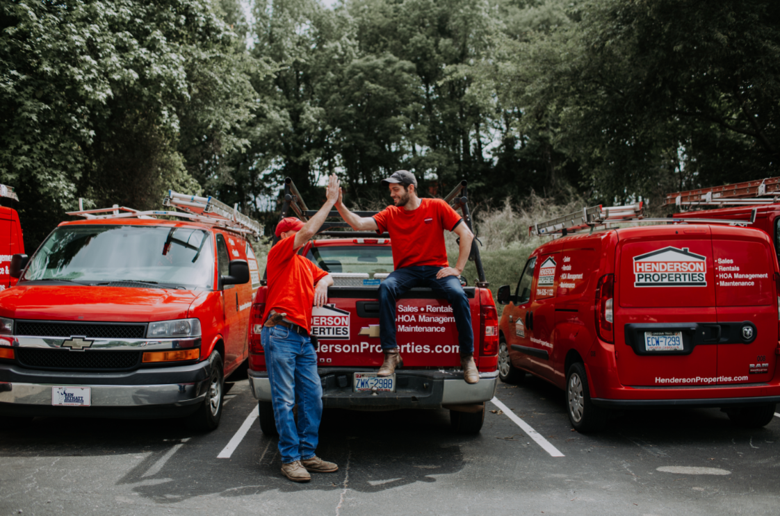 Two people beside red Henderson Properties service vehicles