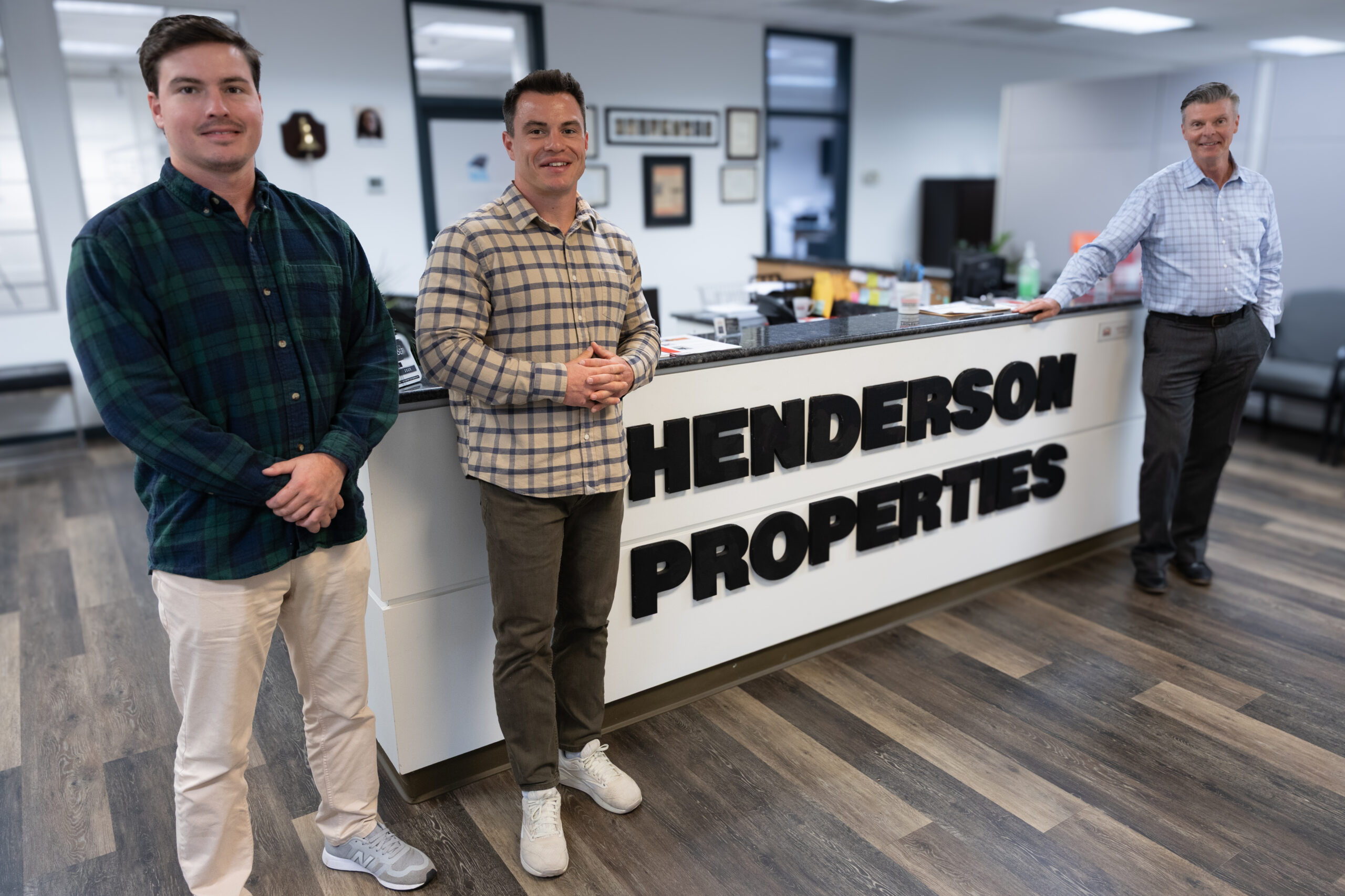Three people standing beside the Henderson Properties reception desk