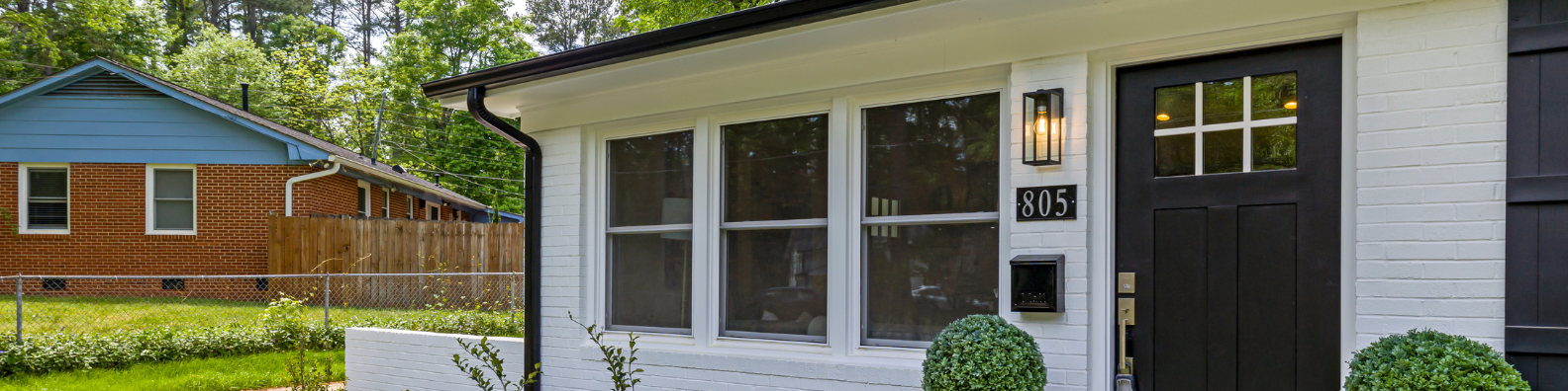 White brick home with a black front door and landscaped front entry